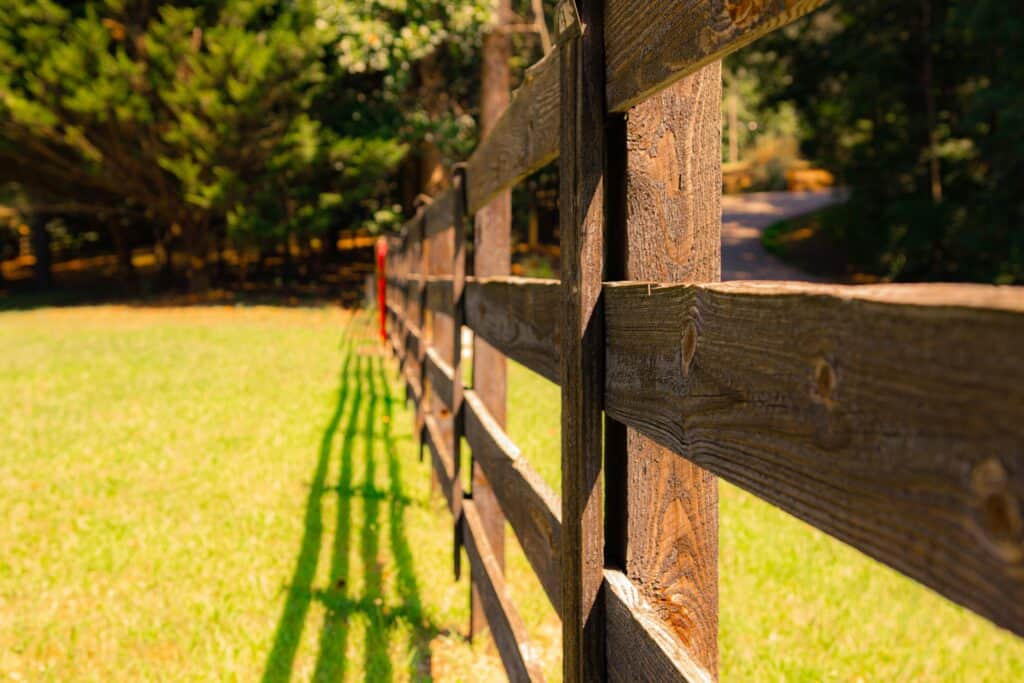 Wooden fence casting shadows on grass